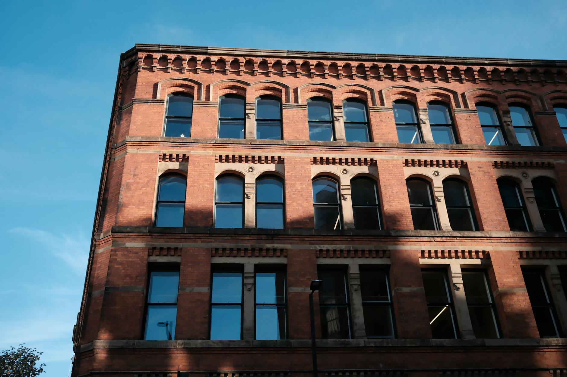 A historic red brick building with arched windows under a clear blue sky, showcasing architectural heritage.